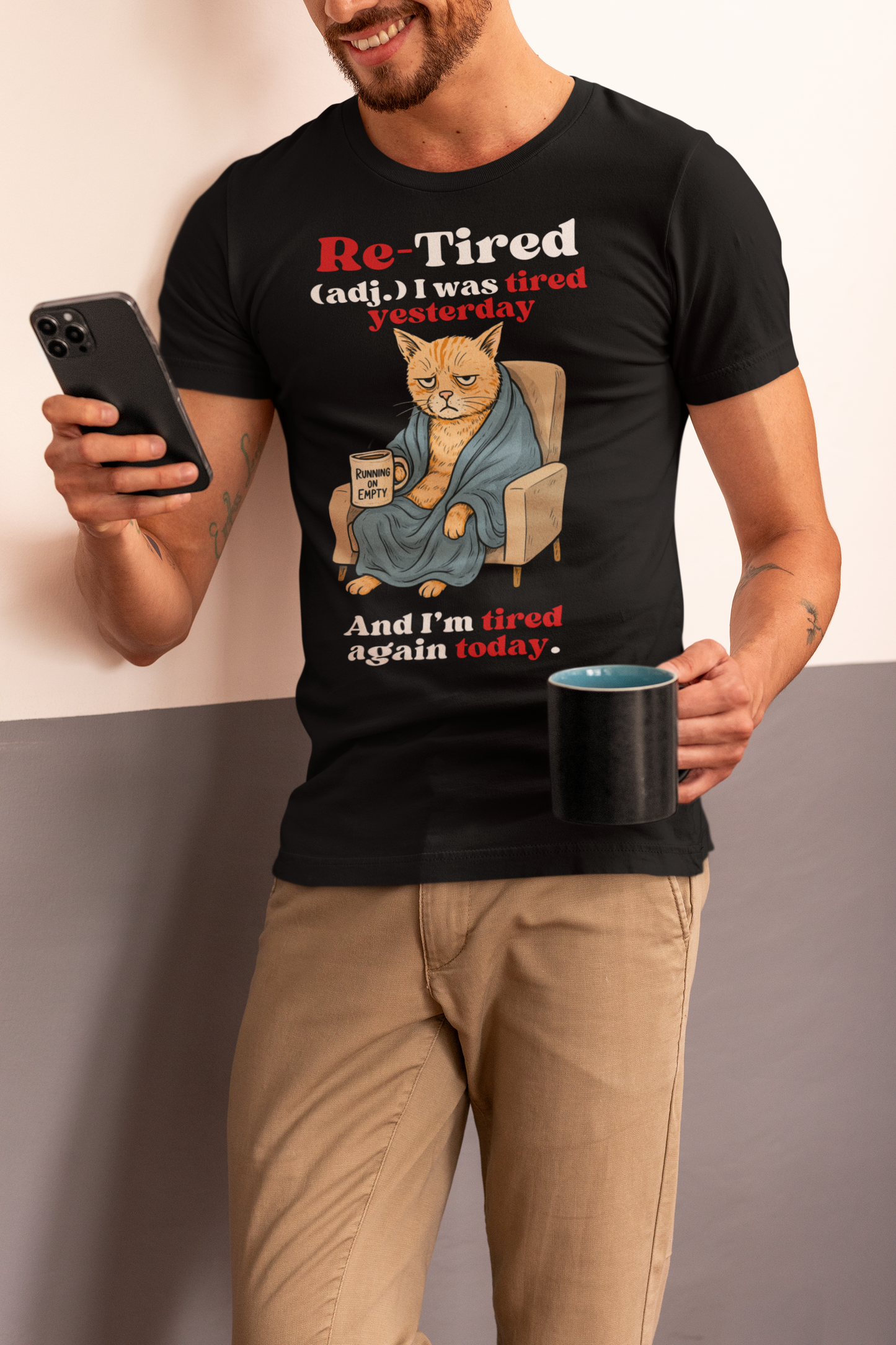 Man wearing a black “Re-Tired” t-shirt featuring a grumpy orange cartoon cat wrapped in a robe and holding a “Running on Empty” coffee mug. Humorous Father’s Day shirt for tired dads, cat lovers, or sarcastic pet dads.