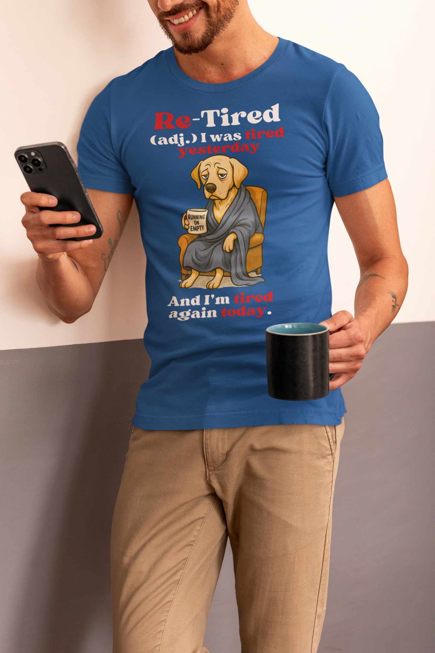 Smiling man wearing a blue“Re-Tired” t-shirt featuring a tired cartoon dog holding a coffee mug that says “Running on Empty,” with the caption “I was tired yesterday and I’m tired again today.” Perfect Father’s Day gift for dog dads, tired dads, or retired men.